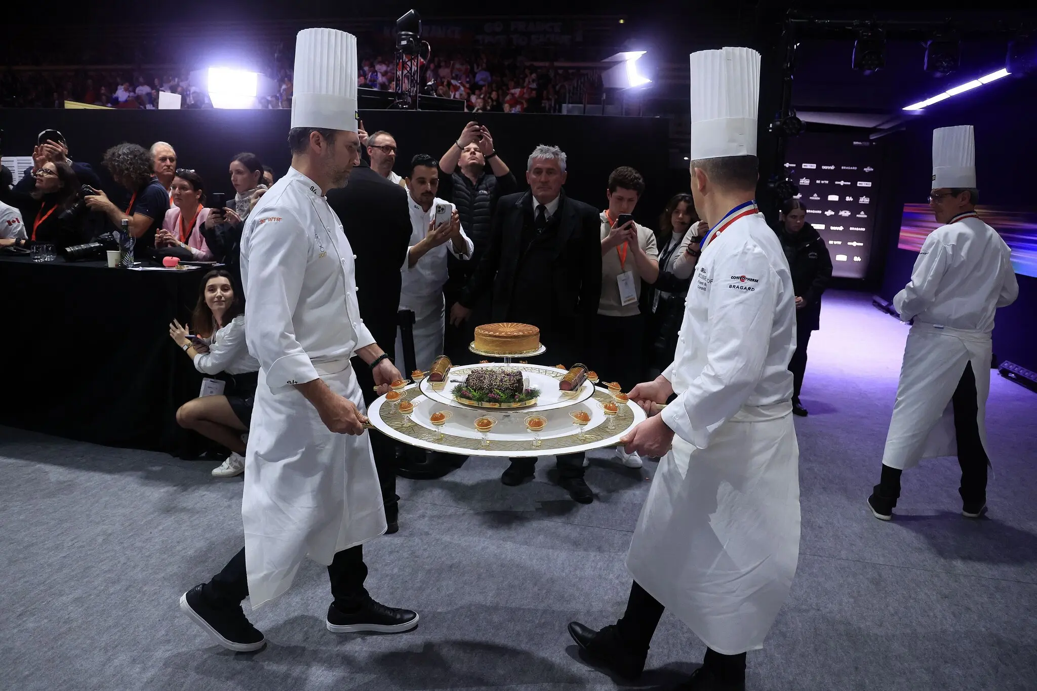 Шеф-кухарі несуть різні страви на презентацію містера Маркона